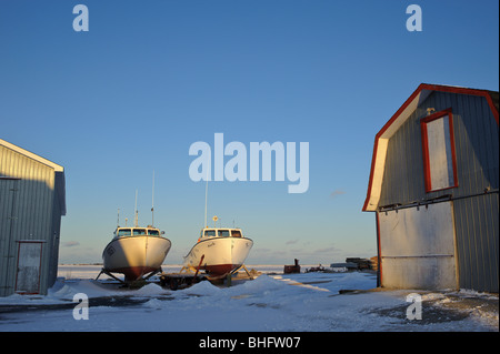 La pesca shack fienile con barche di aragosta fuori dell'acqua accanto a frozen Miramichi Bay in New Brunswick Canada Foto Stock