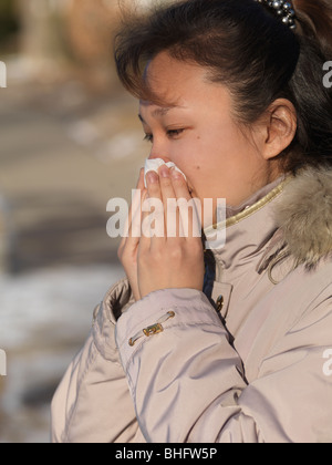 Donna soffia il naso all'aperto in inverno Foto Stock