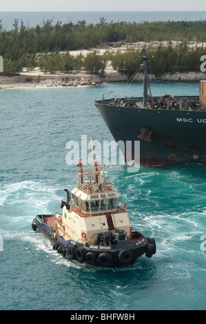 Rimorchiatore 'Svitzer Grand Bahama' appiles potere di prua di 'MSC Uganda' in uno sforzo per manovrare la nave fuori del porto. Foto Stock