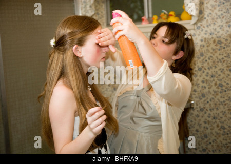 8 classe ragazze preparare per loro ballo formale presso la loro scuola media. Una ragazza mette spray per capelli sui suoi amici capelli; Foto Stock