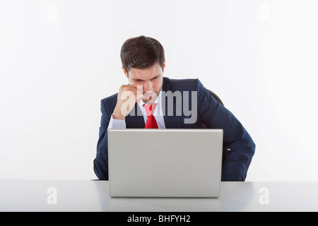 Preoccupato per il business executive in tuta dietro una scrivania con computer portatile Foto Stock