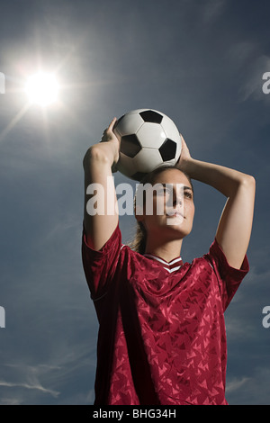 Donna che mantiene il calcio Foto Stock