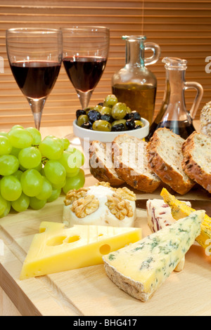 Un piatto di cibo mediterraneo tra cui i formaggi, uva, vino, pane, olive, olio di oliva e aceto balsamico. Foto Stock