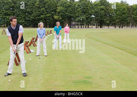 Quattro i golfisti su una gamma di guida Foto Stock