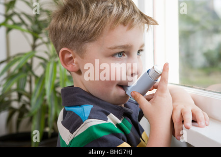 Ragazzo prendendo l'asma inalatore Foto Stock