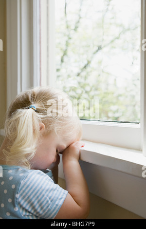 Triste bambina dalla finestra Foto Stock