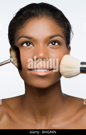 Donna con i pennelli per il trucco sulla faccia Foto Stock