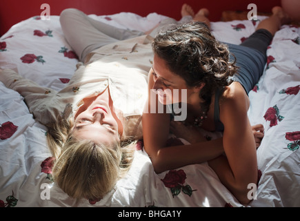 Due donne la posa su letto di parlare Foto Stock