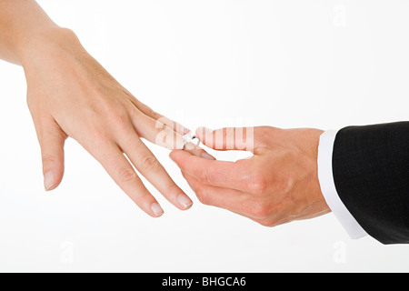 Lo sposo posizionando l'anello sul dito spose Foto Stock