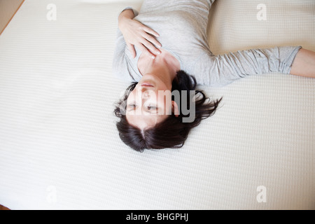 Donna sdraiata sul letto Foto Stock