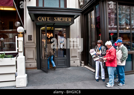 I turisti con mappa fuori dall'hotel e il Cafe Sacher nel centro di Vienna Austria Foto Stock