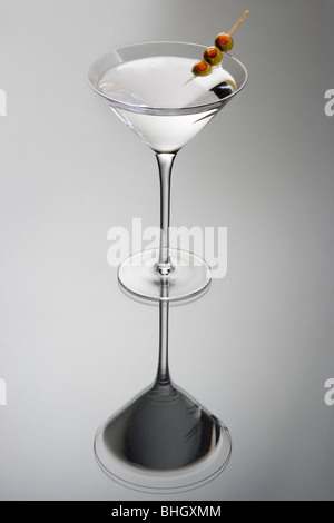 Martini bevanda miscelata con olio di oliva guarnite su uno sfondo grigio chiaro con la riflessione Foto Stock