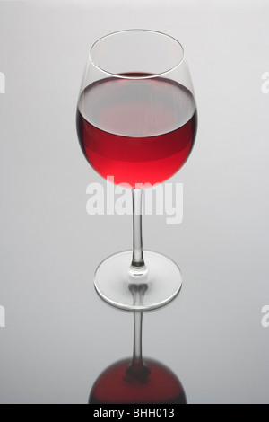 Vino rosso in un bicchiere su un semplice sfondo grigio Foto Stock
