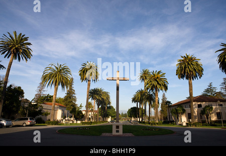 Croce circondata da palme e nella parte anteriore della missione di Santa Clara de Asís, Santa Clara University, Santa Clara, California Foto Stock