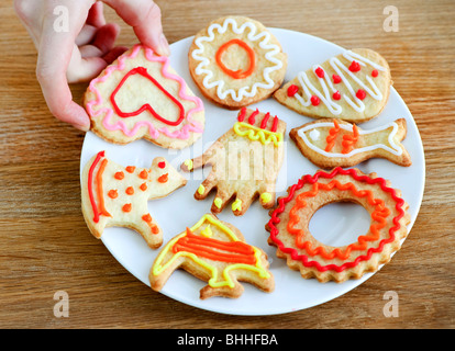 Tenendo la mano cookie dalla piastra di fatti in casa biscotti frollini con glassa Foto Stock