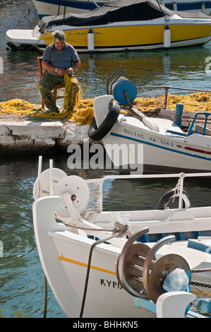 Un pescatore rammendo reti sulla banchina del porticciolo presso Ayios Nikolaos, nella parte esterna di Mani, sud del Peloponneso, della Grecia. Foto Stock