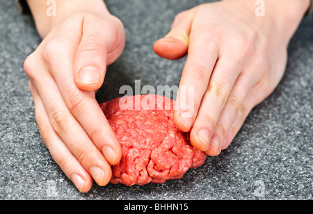 Lo Chef rendendo hamburger patty in cucina con carne macinata di manzo Foto Stock