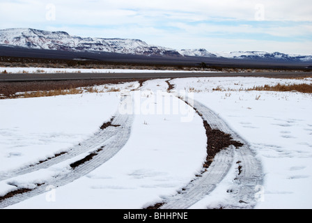 Tracce di pneumatici lasciando la neve sul lato di due corsie in Nevada Foto Stock