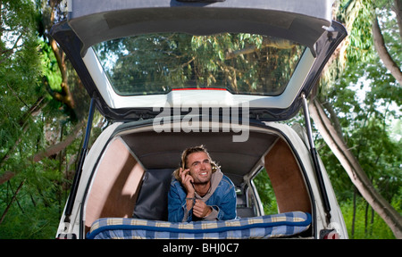 Giovane uomo in auto con auricolare, boschi Foto Stock