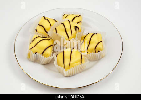 Piastra bianca con sei Signor Kipling Limone fantasie francese torte a base di pan di spagna con topping alla vaniglia Foto Stock