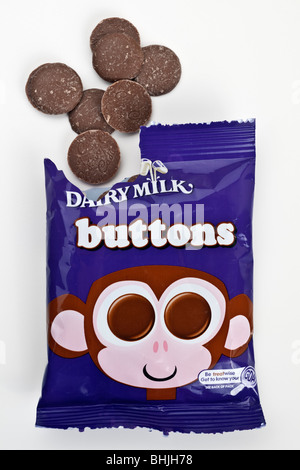 Aprire il sacchetto di Cadburys Dairy milk chocolate sversamento di pulsanti su una superficie bianca Foto Stock