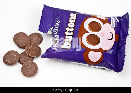 Aprire il sacchetto di Cadburys Dairy milk chocolate sversamento di pulsanti su una superficie bianca Foto Stock