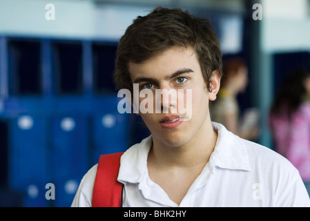 Maschio di studente di scuola superiore in piedi nella hall rivestita con armadietti, ritratto Foto Stock