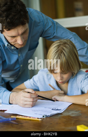 Maschio alta junior student guarda come insegnante di assegnazione dei controlli, close-up Foto Stock