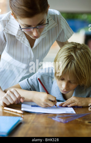 Insegnante guardando sopra studente della spalla di rivedere i loro incarichi Foto Stock