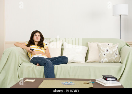 Ragazza adolescente con telecomando contemplatively guardando lontano Foto Stock