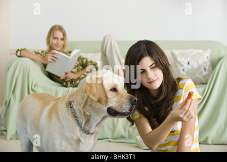 Ragazza adolescente offrendo biscotto cane per cane Foto Stock