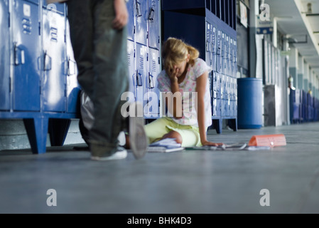 Junior high studente seduto sul pavimento a piangere, ragazzo che sta guardando Foto Stock