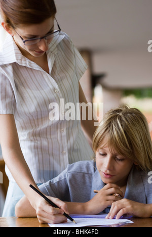 Aiutando l'insegnante di scuola elementare studente in classe Foto Stock