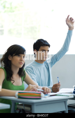 Gli studenti delle scuole superiori in classe, teen boy alzando la mano Foto Stock