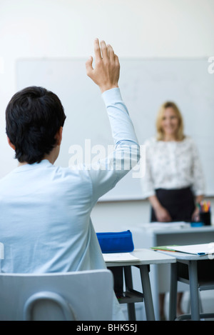 Studente di scuola superiore alzando la mano in classe Foto Stock