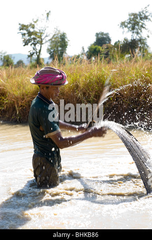 Un povero cambogiano lavoratore di riso con attività di pesca in una diga per proteina cibo da mangiare. Foto Stock