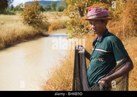 Un povero cambogiano lavoratore di riso con attività di pesca in una diga per proteina cibo da mangiare. Foto Stock