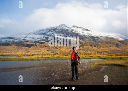 Escursionista sorge sulla riva del lago Abeskojavri in autunno, Kungsleden trail, Lapponia, Svezia Foto Stock