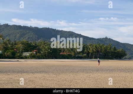 Persona passeggiando su una spiaggia deserta Foto Stock