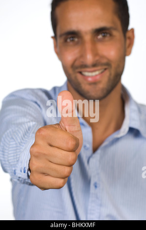 Felice giovane uomo dando un pollice in alto gesto contro uno sfondo bianco Foto Stock