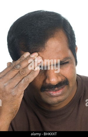 Uomo indiano con un mal di testa contro uno sfondo bianco Foto Stock