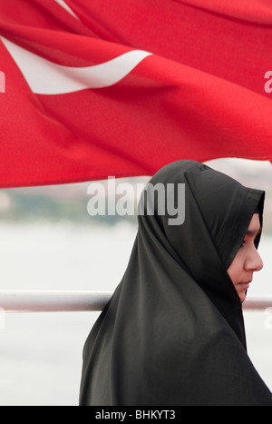 Una giovane donna che indossa un hijab sorge di fronte al Bagno Turco bandiera nazionale Foto Stock