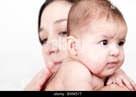 Bella ispanica caucasica Latina azienda madre drooling baby sulla spalla e maschiatura sul retro in modo bambino può burp, isolata. Foto Stock