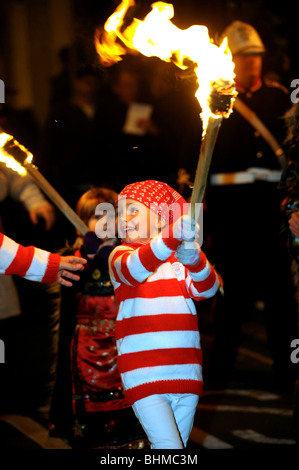 Lewes notte dei falò celebrazioni un bambino piccolo tenendo una torcia ardente di prendere parte alla parata Foto Stock