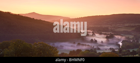 La nebbia indugia nel Usk Valley all'alba guardando verso la montagna Sugar Loaf, Parco Nazionale di Brecon Beacons, Powys, Wales, Regno Unito. Foto Stock