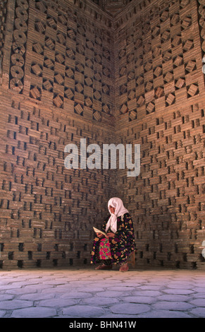 Uzbek donna studio Corano (islamico Bibbia) all'interno del mausoleo di Ismail Samani, Bukhara, Uzbekistan Foto Stock