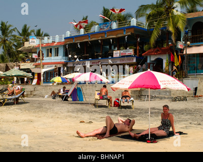 India Kerala, Kovalam, Faro (ADAM) spiaggia, turisti occidentali a prendere il sole in ombra del parasole Foto Stock