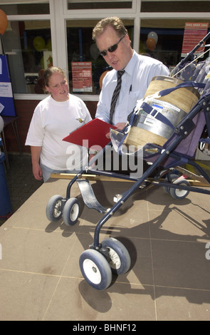 Trading standards officer mostra una giovane mamma come per vedere se il suo passeggino conforme alla legge UK Foto Stock