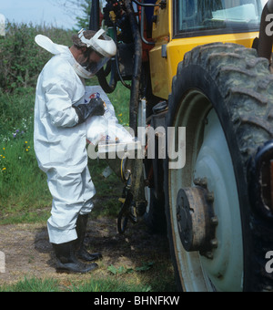 Lavoratore che indossa protettivo completo riempimento ingranaggi serbatoio su Gem 2000 Irroratrice montata sul trattore Fastrac Foto Stock