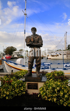 Statua di un giovane pescatore di spugna sta davanti a una flotta di spugna di barche da pesca al Tarpon Springs Harbour Foto Stock